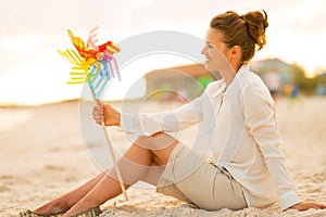 Woman with colorful windmill toy sitting on beach