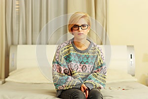 Woman in colourful sweater sitting on the bed