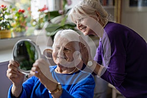 Woman combing hair of elderly mother