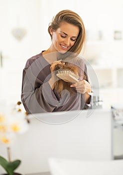 Woman combing hair and looking on hair ends