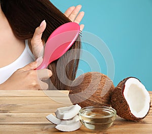 Woman combing her healthy hair and natural coconut oil on wooden table