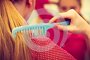 Woman combing her long hair in bathroom