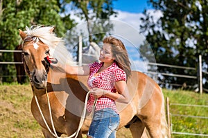 Woman combing pony on horse stable
