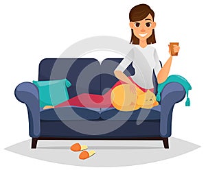 Woman on a comfortable sofa holding cup and stroking her cat