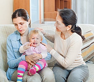 Woman comforting adult daughter with toddler