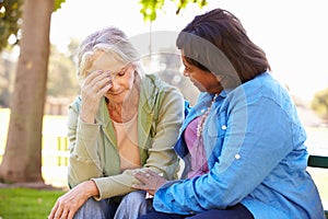 Woman Comforting Unhappy Senior Friend Outdoors photo