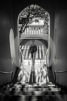 Woman coming down the stairs under a porch with beautiful sunlight and big shadow