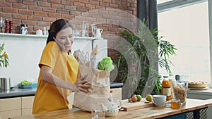 Woman coming home with grocery bags. Pretty girl talking on phone in kitchen.