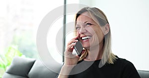 Woman communicates laughing on phone at home