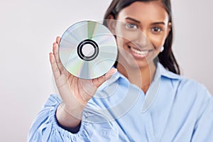 Woman, compact disk and smile in studio portrait for programming, software and information technology. Young indian girl