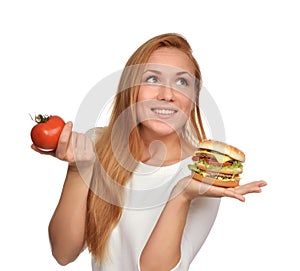 Woman comparing tasty unhealthy burger sandwich in hand and tomato