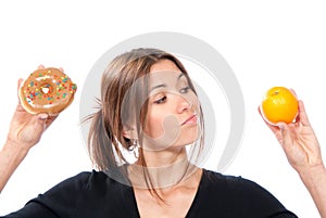 Woman comparing unhealthy donut and organic orange