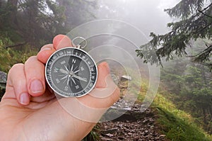 Woman with compass is seeking a right way in forest