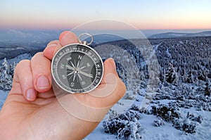 Woman with compass is seeking a right way in mountains