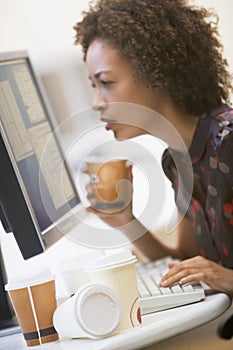 Woman by computer with many cups of empty coffee