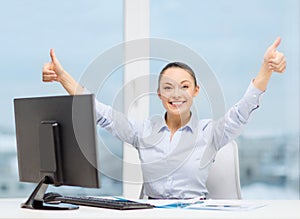 Woman with computer, papers showing thumbs up