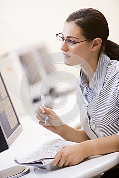 Woman in computer room circling items on newspaper