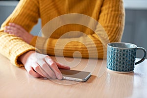 Woman Concerned About Excessive Use Of Social Media Laying Mobile Phone Down On Table