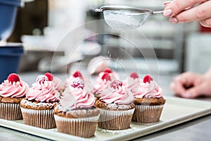 Woman in confectionary icing cupcakes with sugar photo