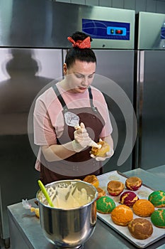 Woman confectioner adding creamy or cheese filling into the choux au craquelin