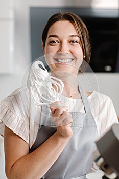 Woman confectioner prepares meringue in the kitchen. Whisk with meringue