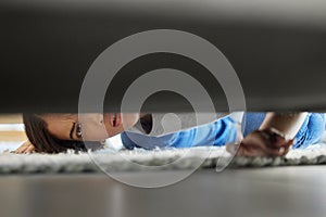 Woman, confused and couch looking for lost product in her home living room with doubt. Female, floor and checking under photo