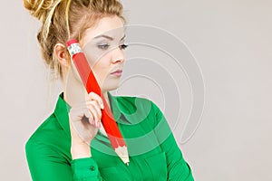 Woman confused thinking, big pencil in hand