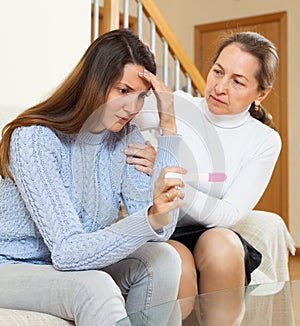 Woman consoling the sad daughter with pregnancy test