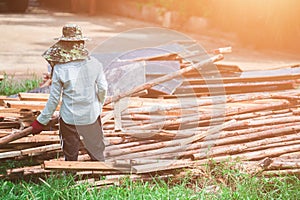 A woman construction laborer carrying wood beam.