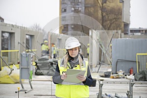 Woman construction site engineer architect worker with hard hat writes notes