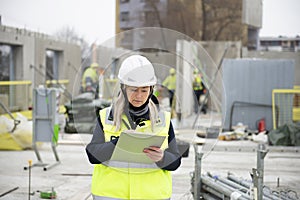 Woman construction site engineer architect worker with hard hat writes notes