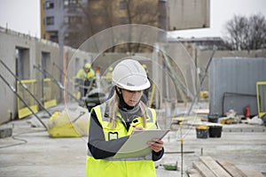 Woman construction site engineer architect worker with hard hat writes notes on the progress of work