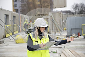 Woman construction site engineer architect worker with hard hat writes notes on the progress of work,real people