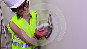 Woman construction worker grind the wall