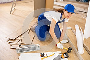 Woman construction worker setting wooden laminate board on floor