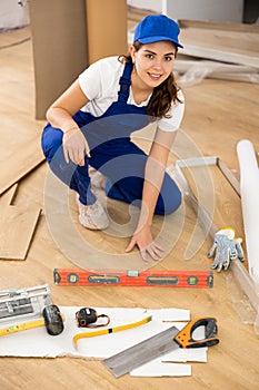 Woman construction worker setting wooden laminate board on floor