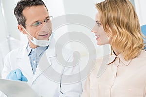 Woman consulting with doctor pointing at clipboard in modern