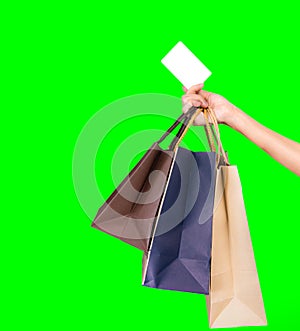 Woman consumer hand holding colorful shopping bag and credit card isolated on green background. Consumerism concept. Asian woman