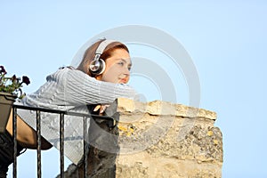 Woman contemplating from balcony listening to music