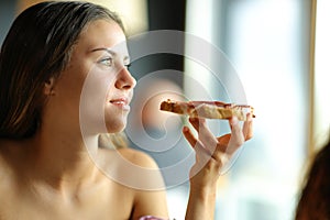 Woman contemplating holding toasted bread with ham