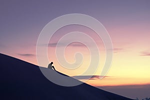 Woman contemplating the horizon in the desert from atop a dune against a golden sky at sunset.