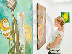 Woman contemplating paintings in art gallery photo