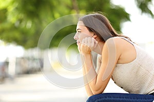 Woman contemplating sitting in a bench