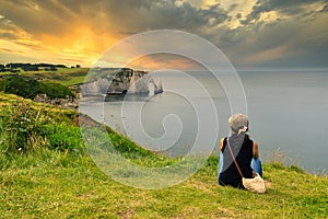 Woman contemplating sunset over the Etretat bay