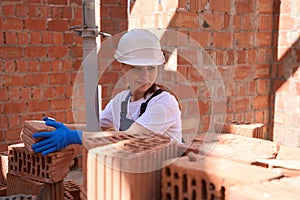 Woman contractor sorting bricks and checking quality of building materials