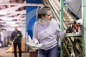 Woman controlling gages of equipments on olive oil factory