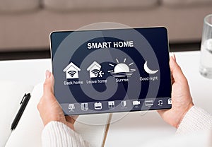 Woman controlling smart home with devices using digital tablet with launched app with icons