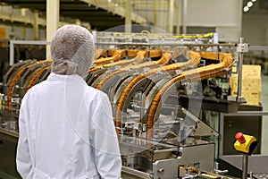 A woman controls the production process. Large biscuit factory. A line of biscuits in a large factory. Packing crackers