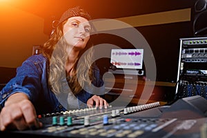 A woman controls the sound mixer. The girl at the remote in the recording Studio. Professional vocal recording at the Studio
