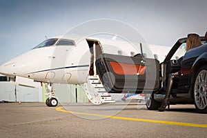 Woman convertable car and corporate private jet photo